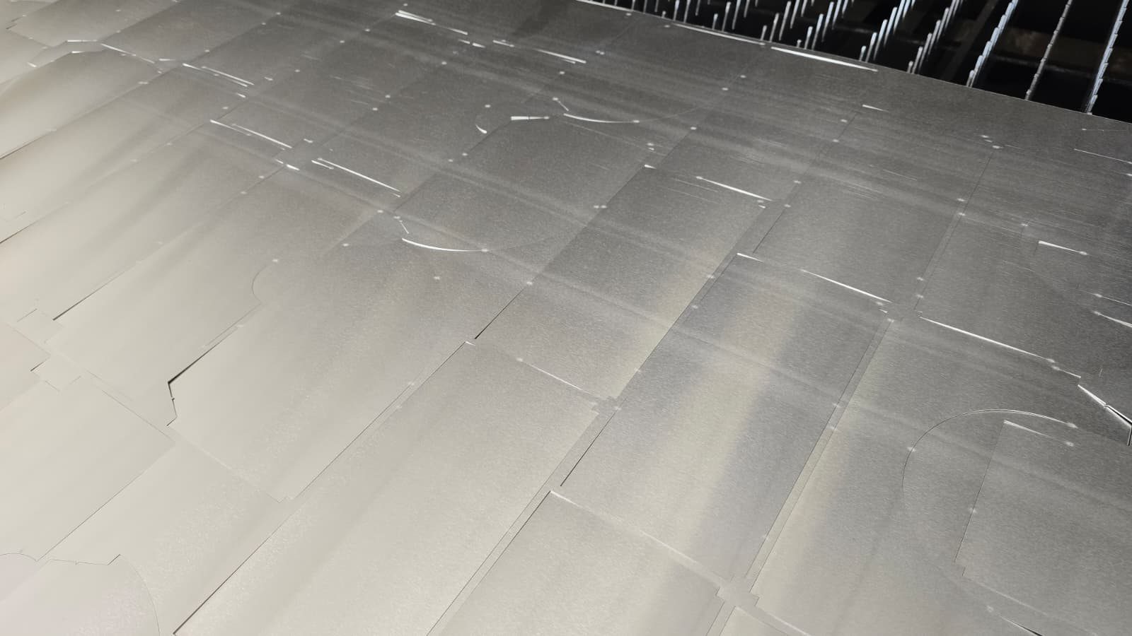 Cut aluminium sheet on the cutting machine table: the cladding parts held in the sheet by micro-joints